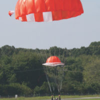man lands in landing area under red HX-Series canopy