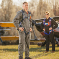 man stands in front of vintage aircraft with Butler back parachute