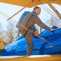 man climbs in vintage aircraft wearing Butler back parachute