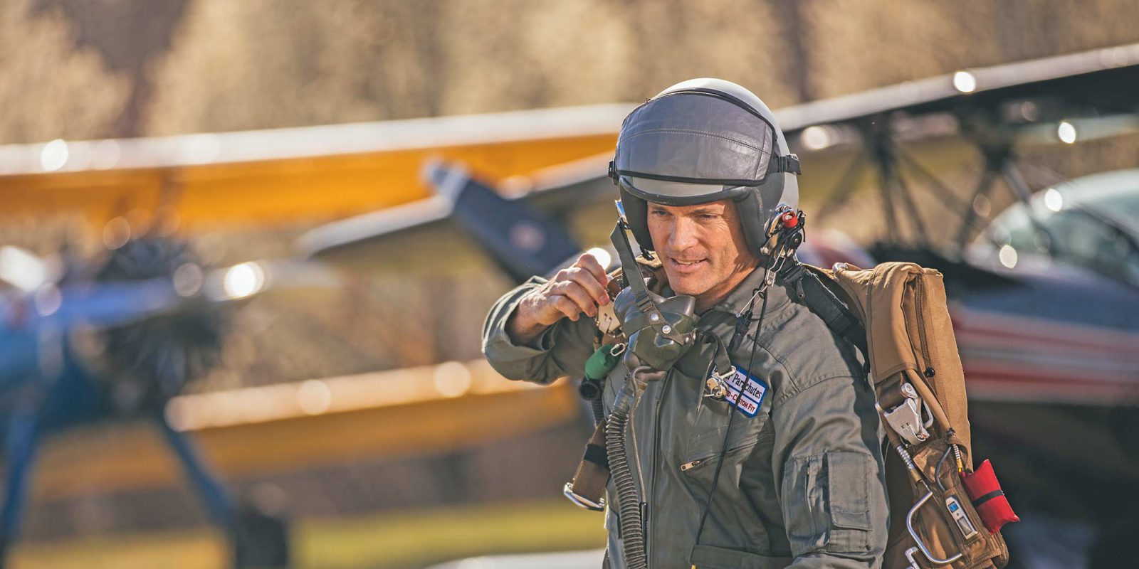 flight test pilot walks to plane wearing helmet and Butler emergency parachute